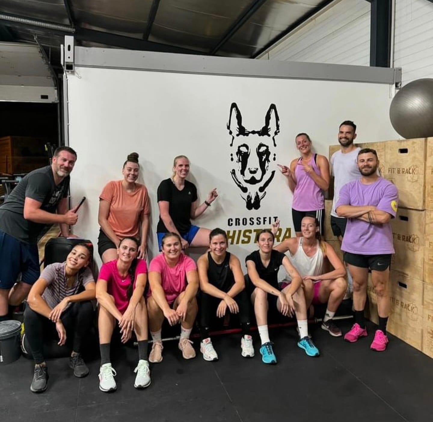 Coachs et athlètes posant devant le logo de la box CrossFit Chistera