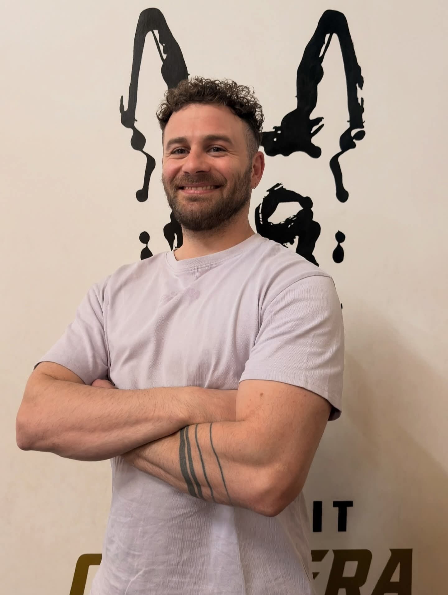 Portrait d'un coach CrossFit Chistera devant la fresque du logo